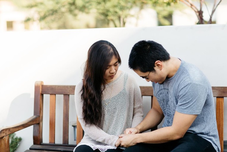 young couple holding hands in prayer