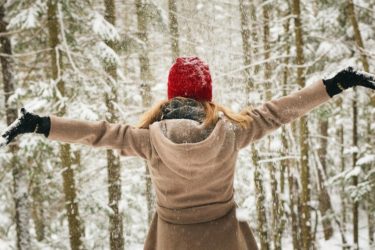 A girl spreads her arms out in the snow.