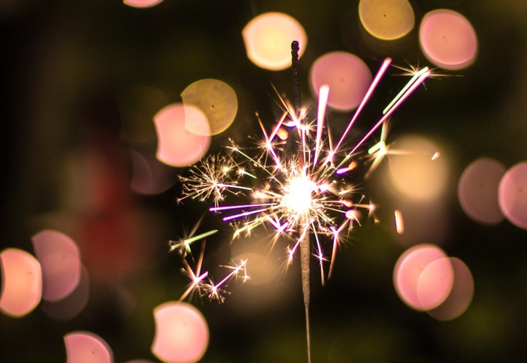 A sparkler with pink and orange blurred background.
