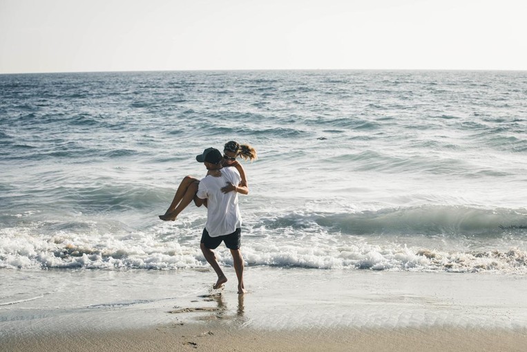 man carrying woman into ocean 
