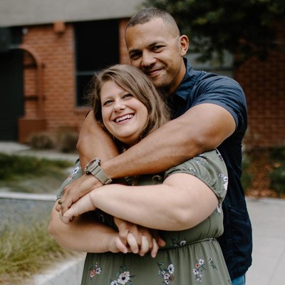 Husband hugging wife from behind, both simling 